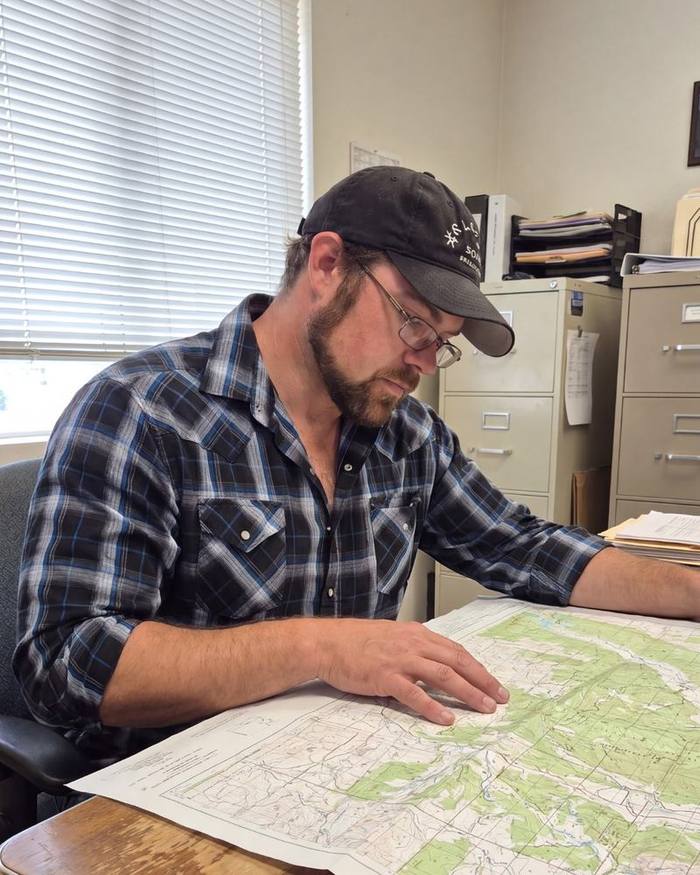 Demitri Stelter studying a topographic map of Delta County at his desk.